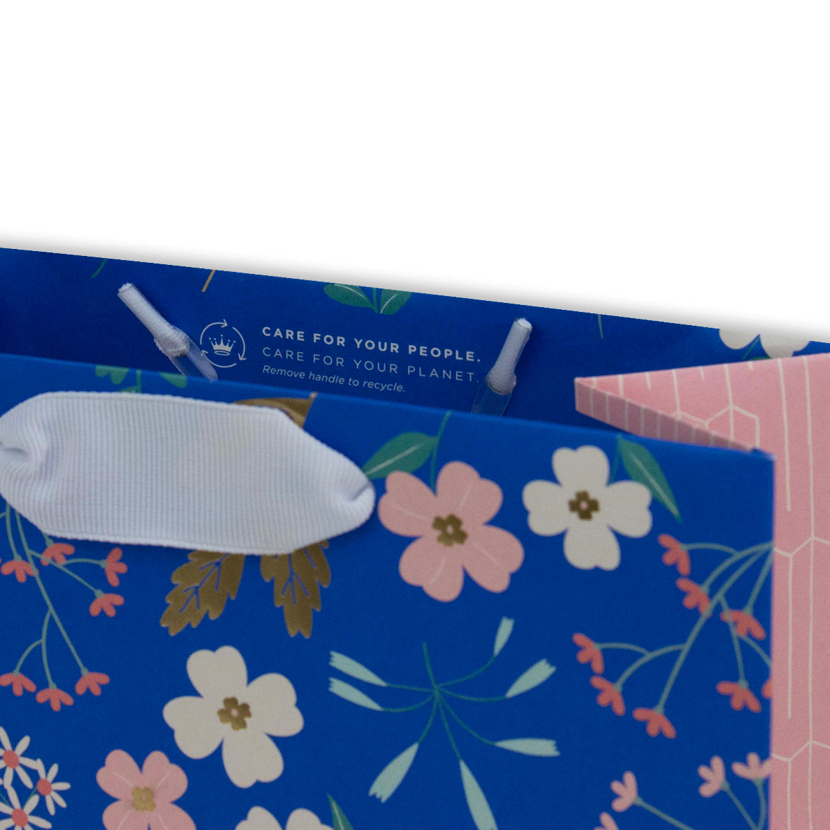 Hallmark Medium Gift Bag - Sky Blue Floral with white ribbon handles and floral design detail, angled view showing care instructions.