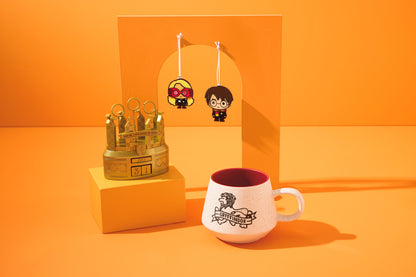 Harry Potter™ Retro Gryffindor™ Mug, 770ml with a speckled finish, alongside character keychains on an orange backdrop.