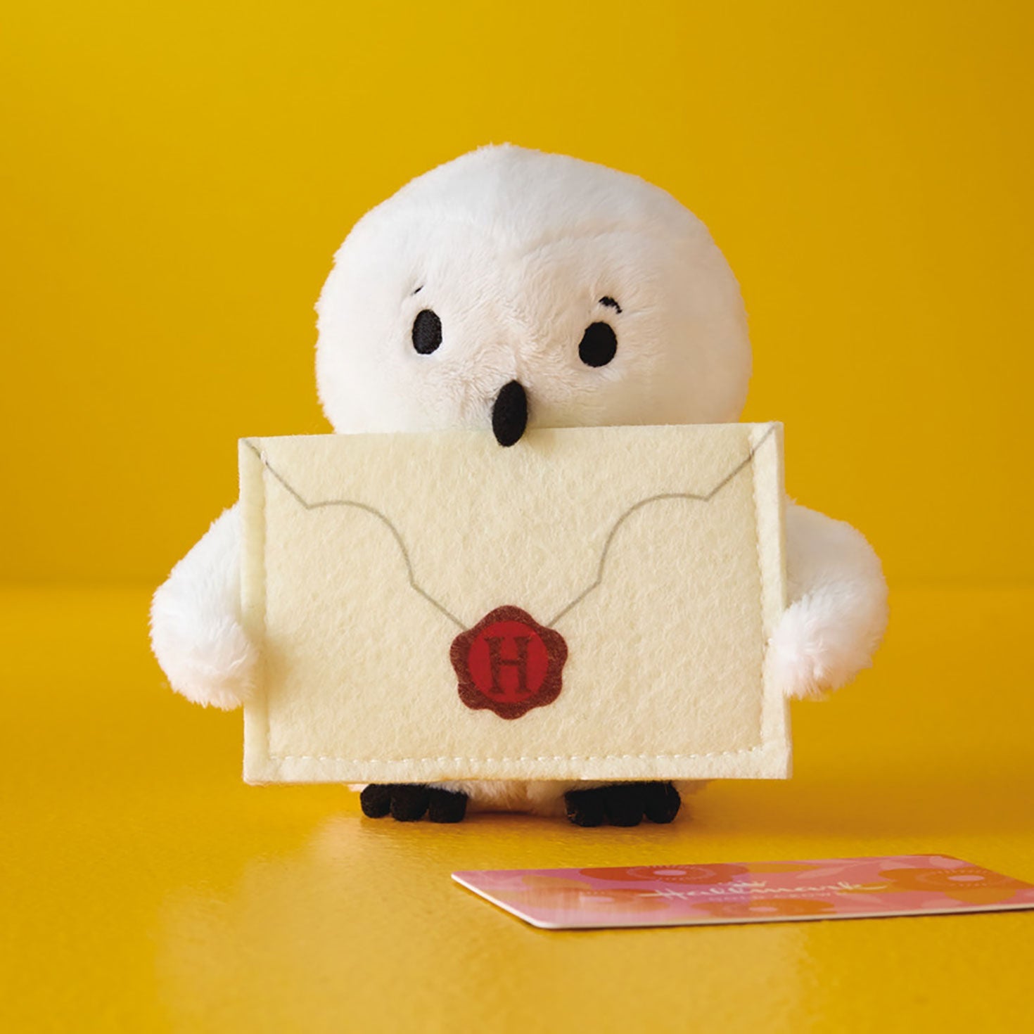 Harry Potter™ Hedwig™ Plush Gift Card Holder, 5" in front of a yellow background, holding a detailed felt envelope.
