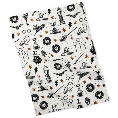 Harry Potter™ Wizarding World™ Icons Tea Towel in white cotton featuring black symbols and gold accents in a flat lay.