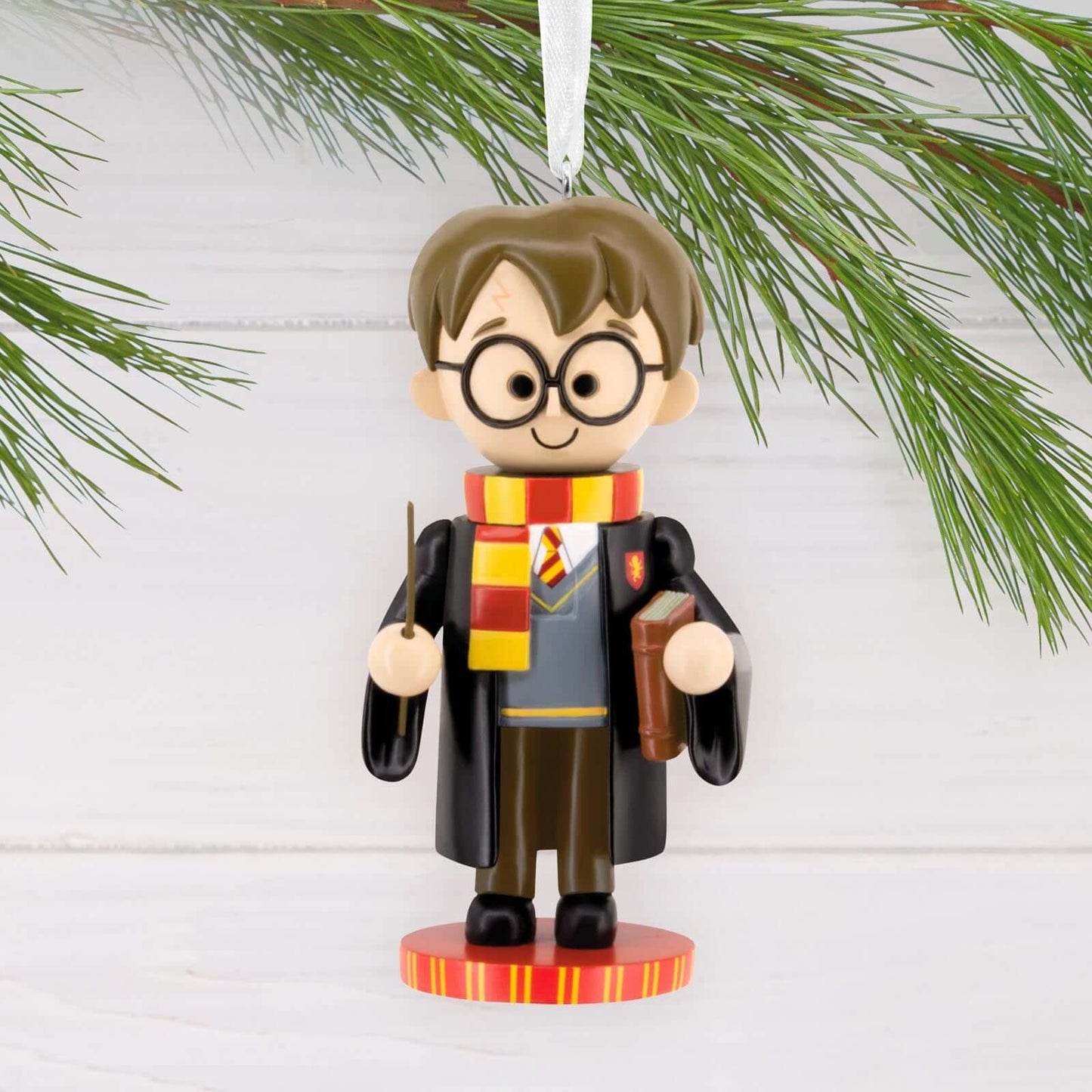 Harry Potter Nutcracker - Hallmark Christmas Ornament, colourful figurine of Harry in Gryffindor robes and scarf, hanging from a pine branch.
