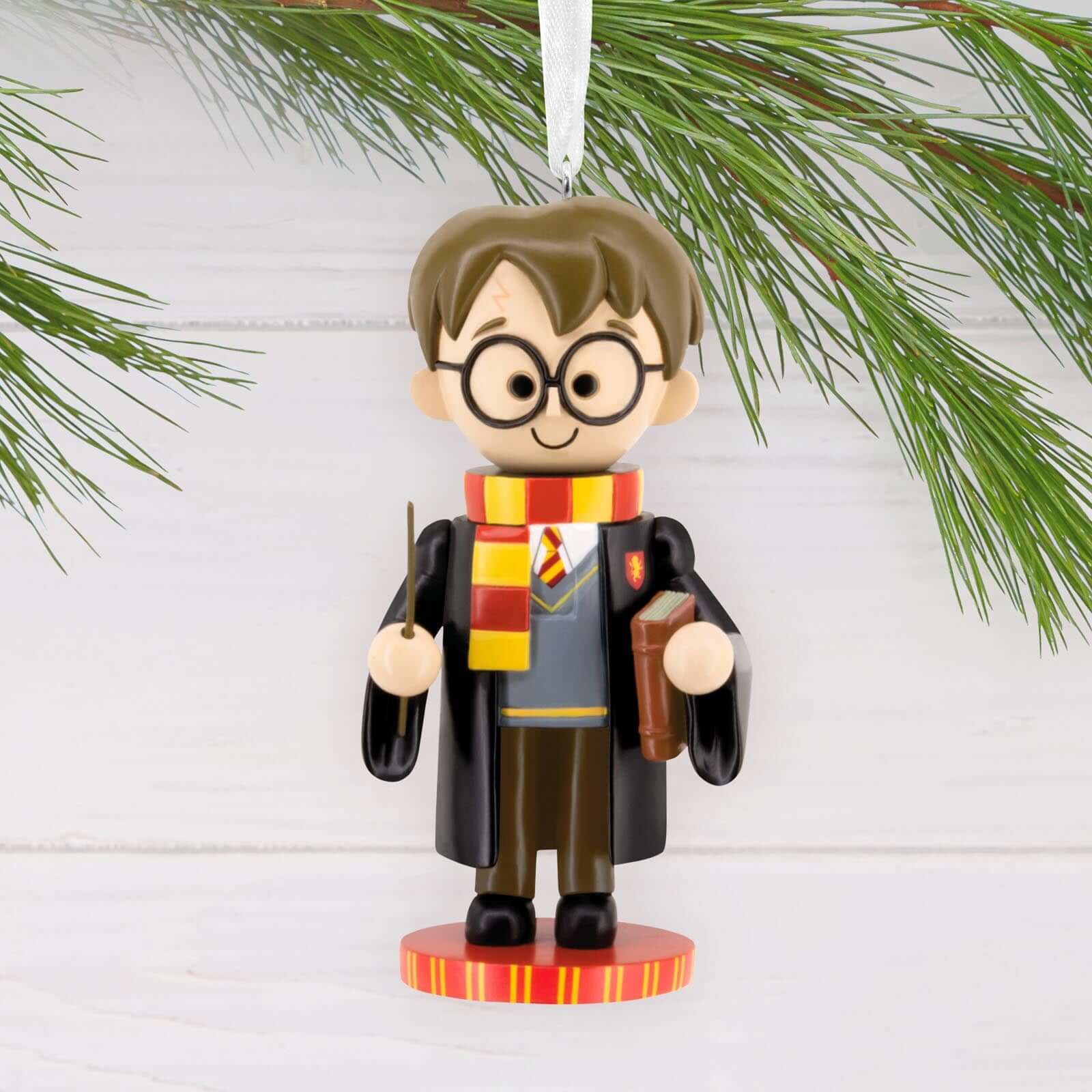 Harry Potter Nutcracker - Hallmark Christmas Ornament, colourful figurine of Harry in Gryffindor robes and scarf, hanging from a pine branch.