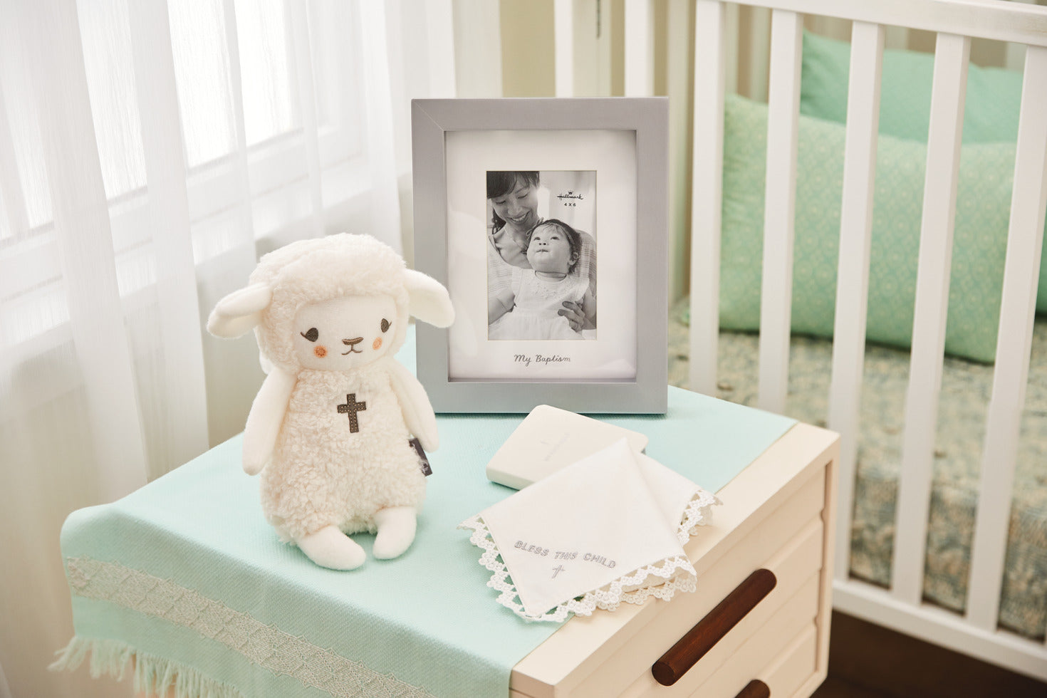 Lullaby Lamb Musical Stuffed Animal, 8.25" on a bedside table beside a framed photo and a white handkerchief.