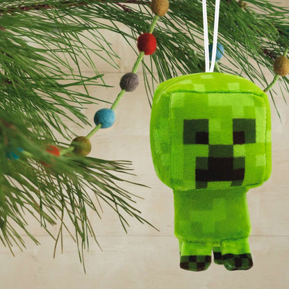 Minecraft Creeper, plush fabric - Hallmark Christmas ornament, hanging from a pine branch with colourful decorations.