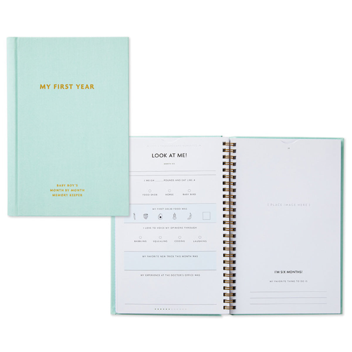 My First Year Baby Book - Blue, fabric-wrapped hardcover, opened pages showing journal prompts and memento sections.