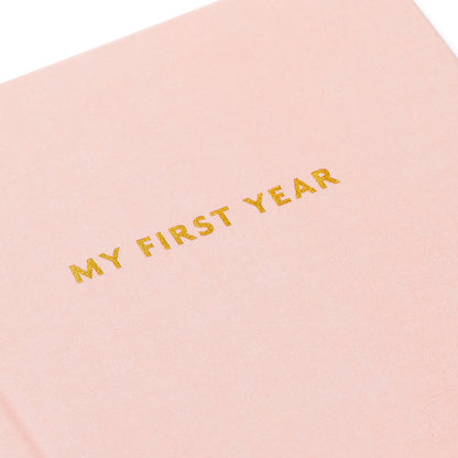 My First Year Baby Book - Pink with golden lettering detail on a soft fabric cover, perfect for documenting a baby girl's first year.