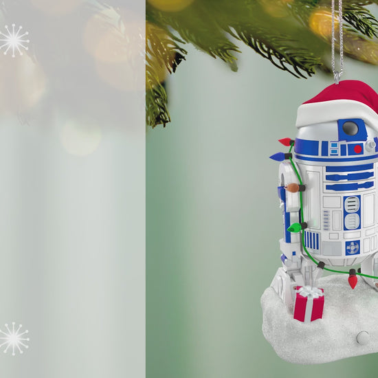 Star Wars™ Decked-Out Droid Musical — 2026 Hallmark Keepsake Christmas Ornament hanging from a tree branch, featuring R2-D2 in a Santa hat and lights.