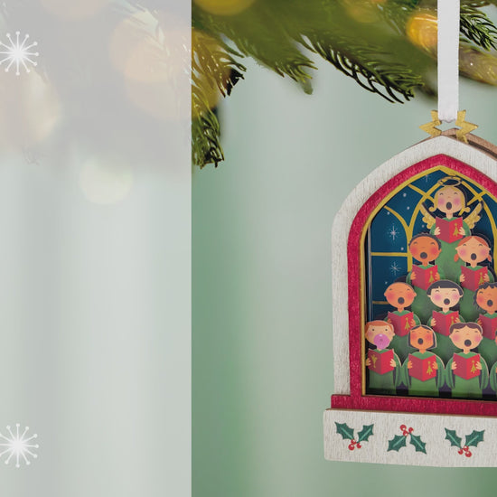 Lifting Their Voices Musical, Papercraft — 2026 Hallmark Keepsake Christmas Ornament, colourful children's choir design, hanging from a tree branch.