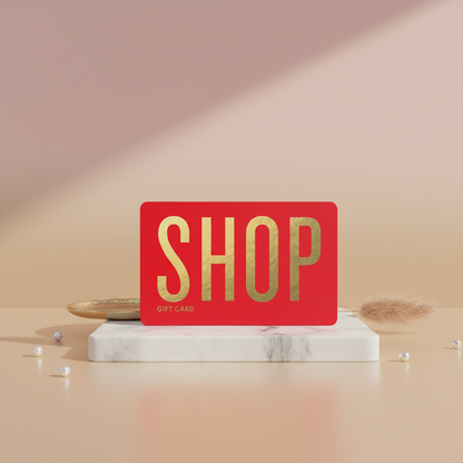Red gift card with 'SHOP' in gold on a marble stand against a pink background