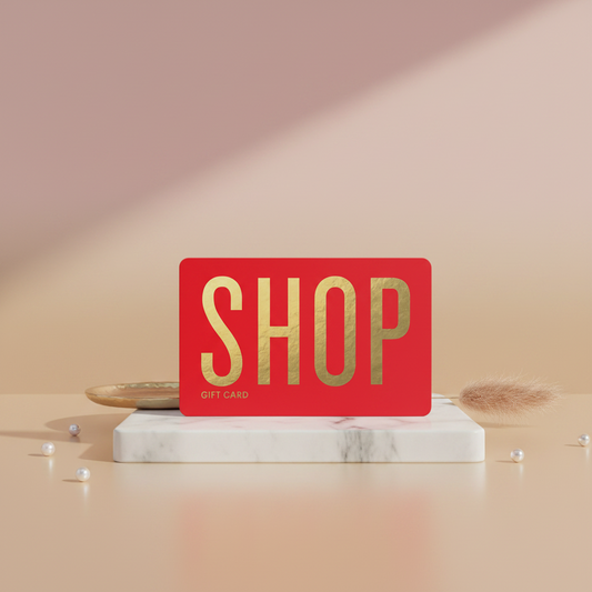 Red gift card with 'SHOP' in gold on a marble stand against a pink background