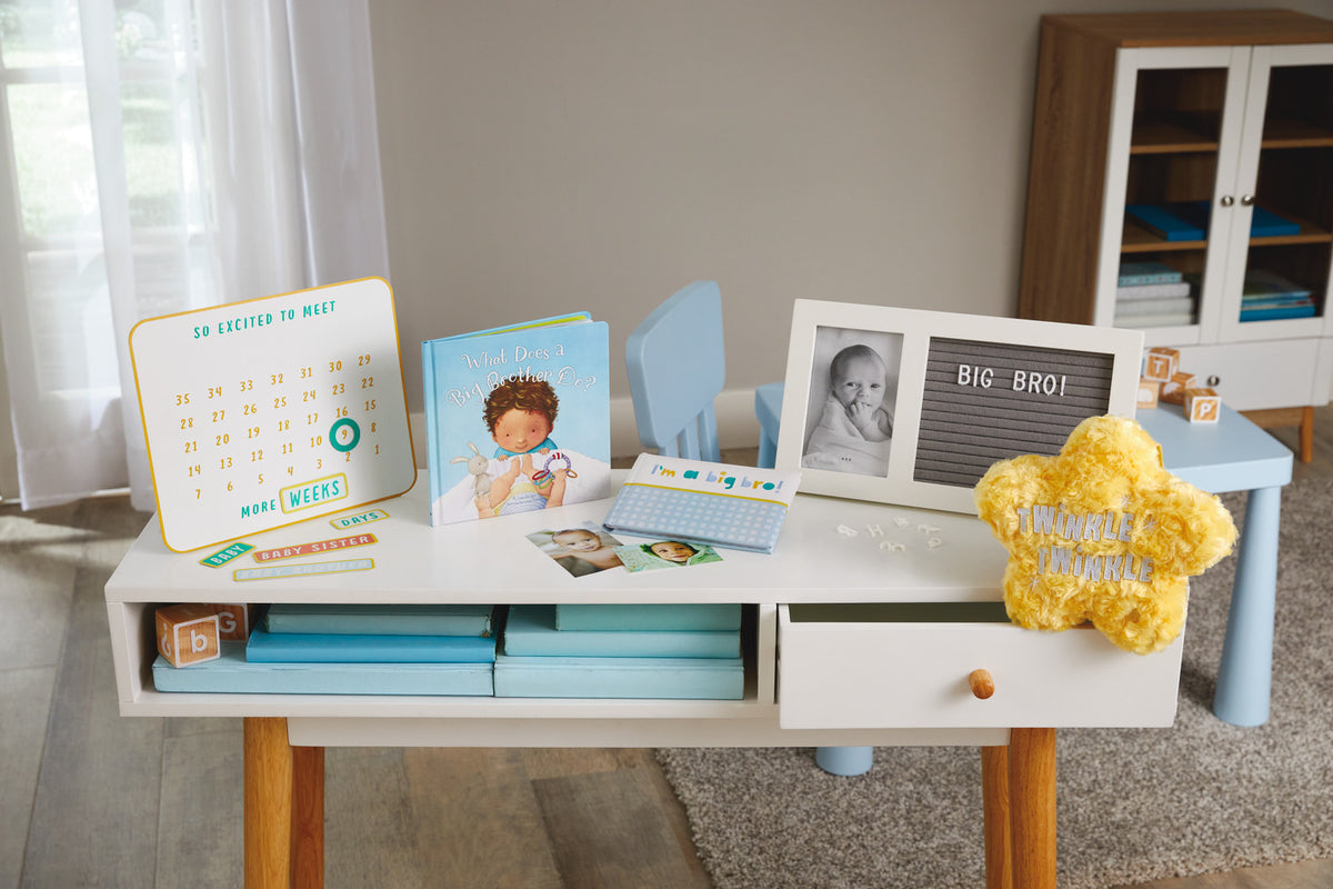 So Excited to Meet You Magnetic Baby Countdown Board displayed on a white desk with a children's book and yellow plush star.