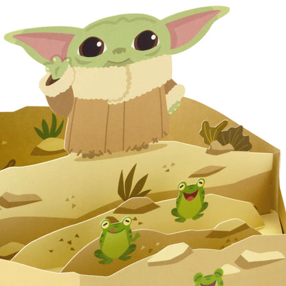 Hallmark Paper Wonder Star Wars™ Baby Yoda Pop Up Father's Day Card, Birthday Card, or Any Occasion (Reaching Out) showing a 3D diorama with Baby Yoda and playful frogs.