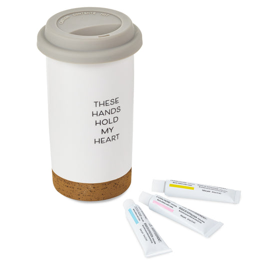 These Hands Hold My Heart Ceramic Travel Mug, 12.5 oz. with cork base, silicone lid, and three paint tubes for DIY decoration.