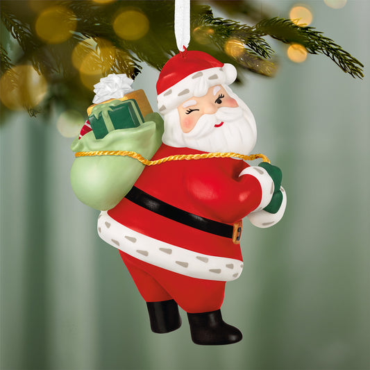 Vintage Santa, Porcelain — 2026 Hallmark Keepsake Christmas Ornament hanging from a tree, featuring a cheerful Santa with a green sack and gift.