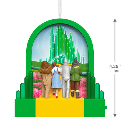 The Wizard of Oz™ Journey to the Land of Oz With Light — 2026 Hallmark Keepsake Christmas Ornament features the Cowardly Lion, Dorothy, Tin Man, and Scarecrow standing together before the Emerald City, measuring 11 cm.