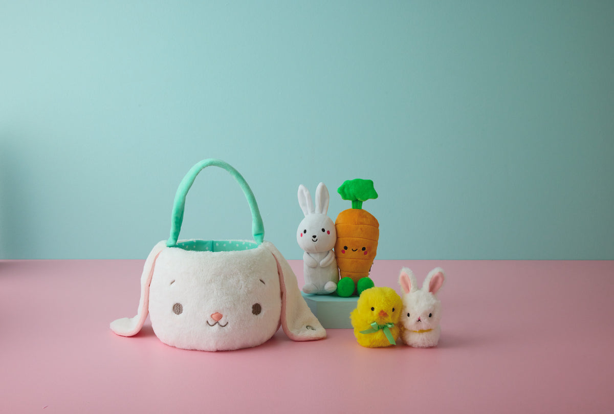 Hallmark Zip-a-Long Bunny Stuffed Animal in cute Easter scene with plush bunny basket, carrots, and baby animals on pink background.