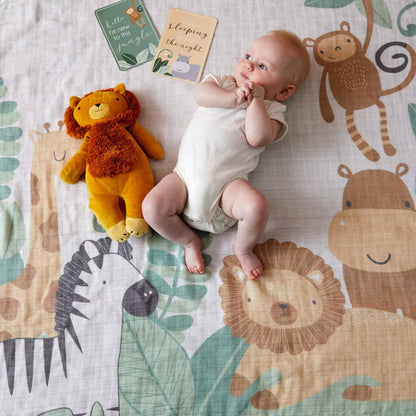 Safari Milestone Muslin Set featuring a baby with plush lion toy on colourful animal print blanket, capturing milestone moments.