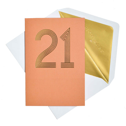 Signature Studio 21st Birthday Card - Here's To You! in coral with gold foil detailing and gold lined envelope, flat lay view.