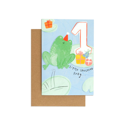 Little Speckled Frog Adorable 1st Birthday Card featuring a cute frog in a party hat with gifts against a blue background, flat lay