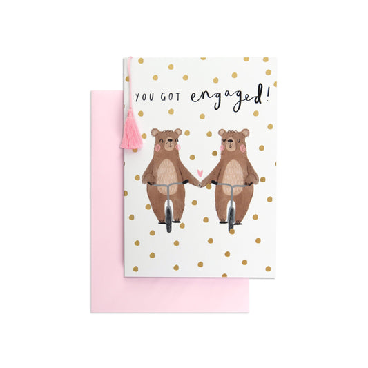 Beary Special Cute Engagement Card featuring two bears on bicycles, light pink envelope, and gold foil polka dots, flat lay view.