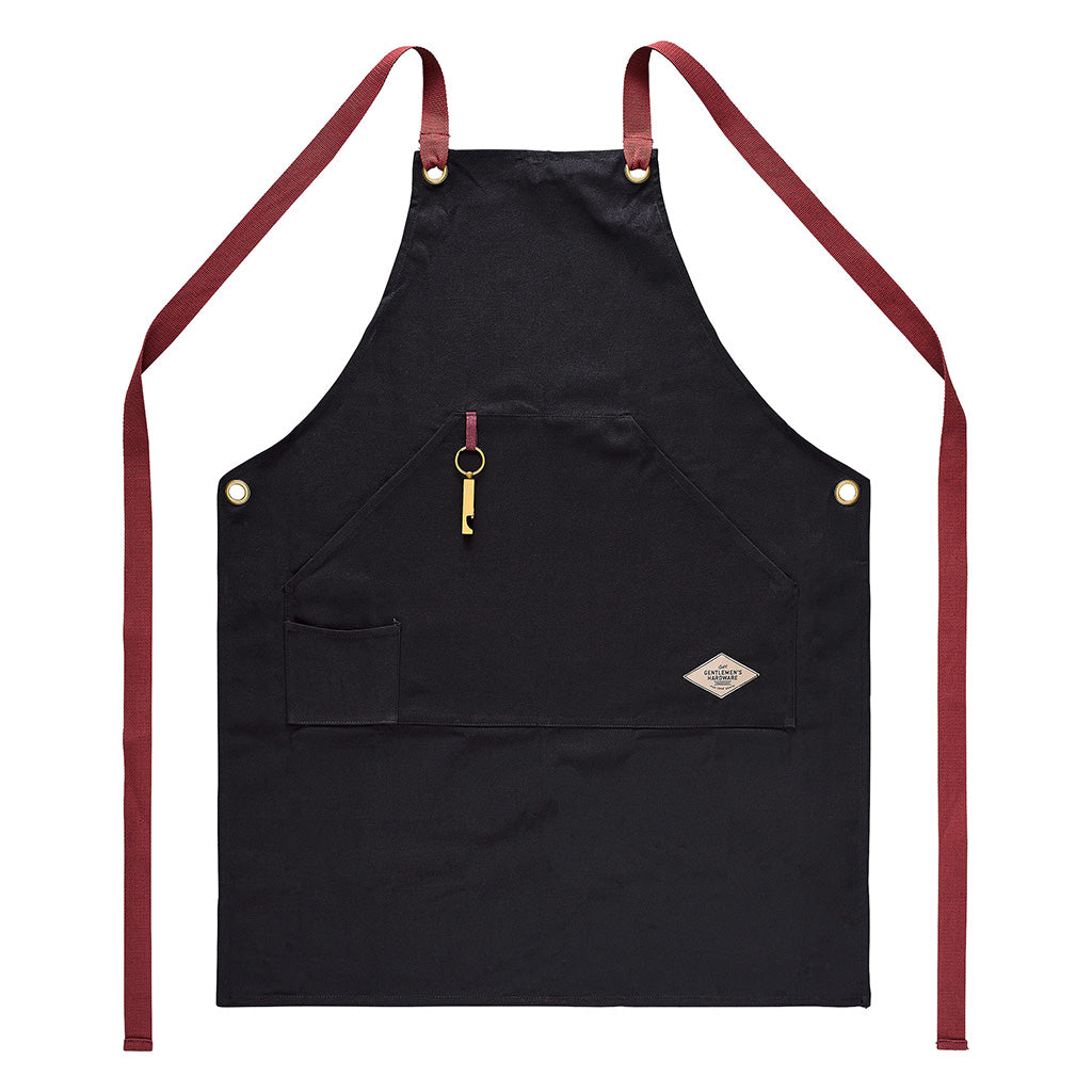 Utility apron & bottle opener in black cotton canvas with red straps, featuring a bottle opener and front pocket, flat lay view.