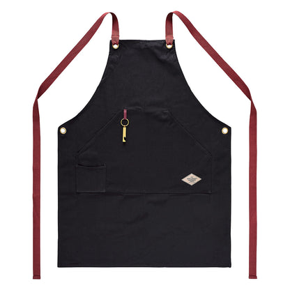 Utility apron & bottle opener in black cotton canvas with red straps, featuring a bottle opener and front pocket, flat lay view.