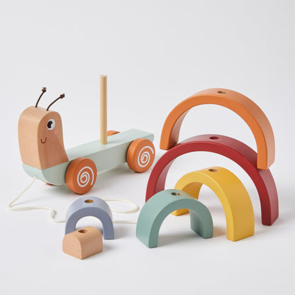 Pull along snail toy made of natural wood with colourful rainbow arches in a flat lay arrangement.