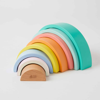 Rainbow Stacker wooden toy in various pastel colours arranged in a playful arch formation, showcasing smooth curves.