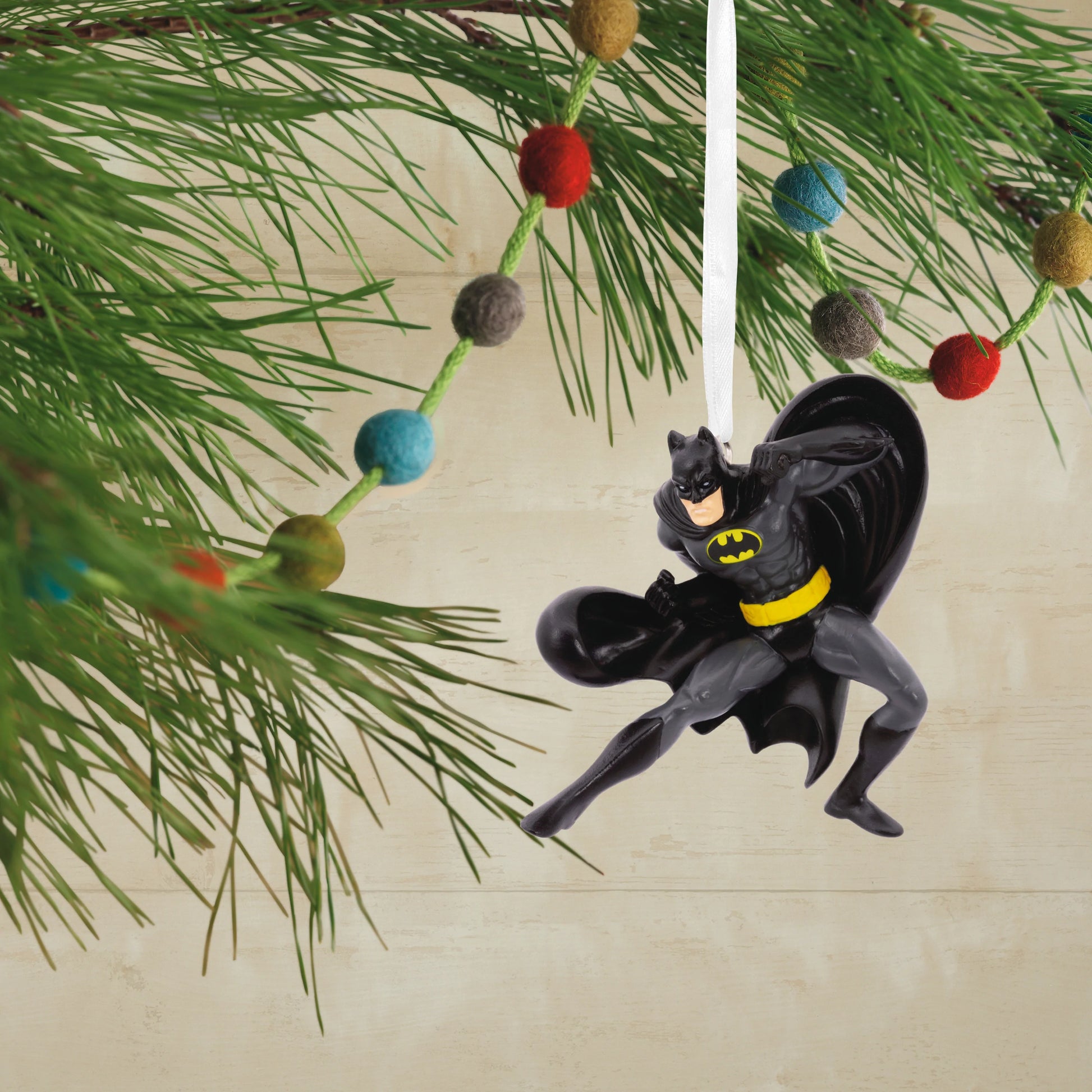 DC Comics Batman - Hallmark Christmas Ornament hanging from a tree branch, featuring Batman in a dynamic pose with a black cape.