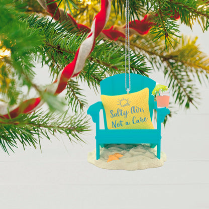 Beach Bliss — Hallmark Keepsake Ornament, beach chair design with a cushion reading ‘Salty Air, Not a Care’, hanging on a Christmas tree.